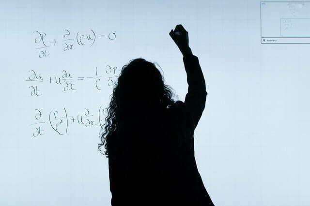 insegnante universitaria scrive su una lavagna luminosa delle formule matematiche